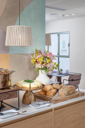 a table with some bread and a vase of flowers at Hotel Carmel  in Haifa
