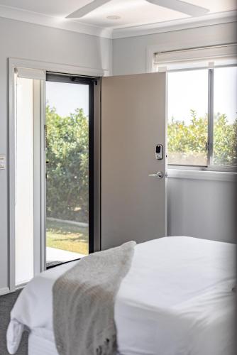 a white bedroom with a bed and a window at Mala Retreat Chardonnay Studio Immaculate and Comfortable in East Maitland