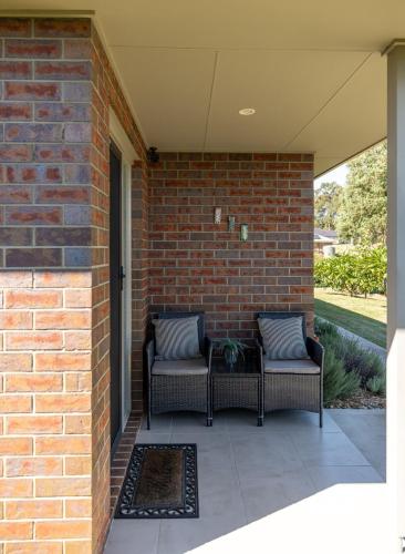 a patio with two chairs and a brick wall at Mala Retreat Chardonnay Studio Immaculate and Comfortable in East Maitland