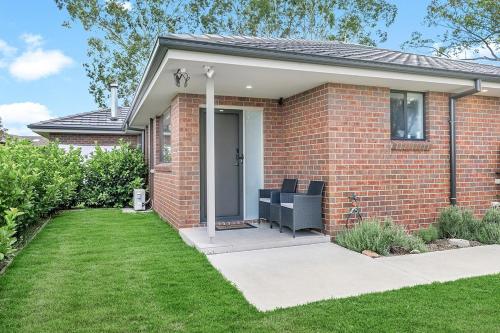 a brick house with a white door and a lawn at Mala Retreat Chardonnay Studio Immaculate and Comfortable in East Maitland