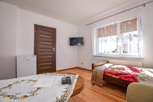 a bedroom with a bed and a table and a window at Domek Na Brzysku Lipnica Wielka in Lipnica Wielka
