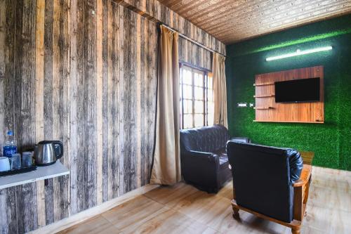 a room with a green wall with a chair and a television at Super Hotel O Champasari Siliguri formerly Four Fox Suits in Siliguri