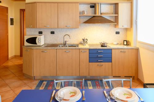 a kitchen with wooden cabinets and a sink and a table at Hotel Garni Le Corti in Grosotto
