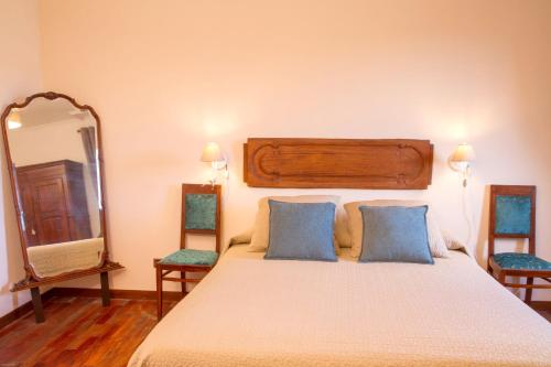 a bedroom with a bed with two chairs and a mirror at Agriturismo Borgo dei Ricci in Impruneta