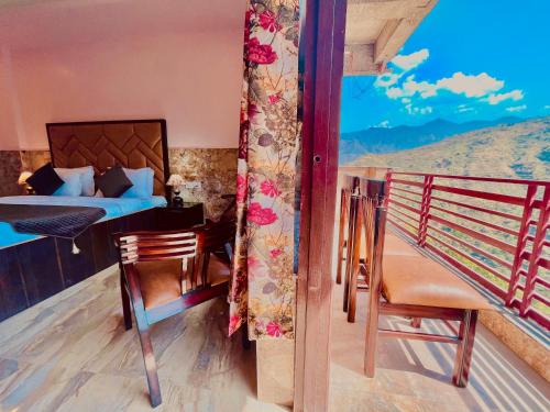 a room with a bed and a balcony with a view at River Grand Resort - A Peaceful Stay Kempty Fall Mussoorie by Sitara Group in Mussoorie