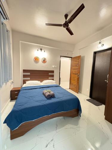 a bedroom with a blue bed with a ceiling fan at Cinnamon Stays Benaulim in Benaulim