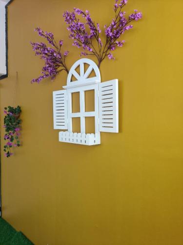 a yellow wall with a window with purple flowers at Cinnamon Stays Benaulim in Benaulim