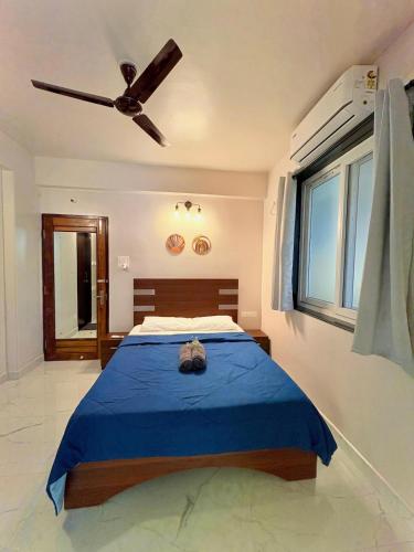 a bedroom with a blue bed with a ceiling fan at Cinnamon Stays Benaulim in Benaulim