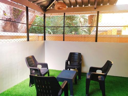 three chairs and a table in a room with grass at Cinnamon Stays Benaulim in Benaulim
