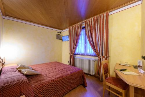 a bedroom with a bed and a desk and a window at Hotel Garni Le Corti in Grosotto