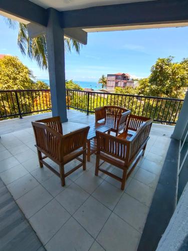 three wooden chairs and a table on a porch at Perhentian Najmi Hotel in Perhentian Island