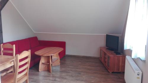 a living room with a red couch and a table at Słoneczna Zagroda - Sunny Ridge Farm in Łączna