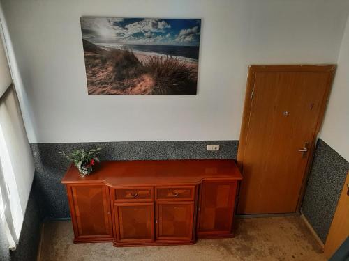 a small wooden cabinet in a hallway with a picture on the wall at Stadtblick 2 Monteuerglück in Eisenberg