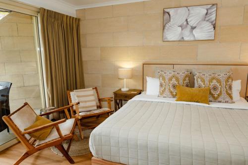 a bedroom with a large bed and two chairs at Portside Motel in Port Campbell