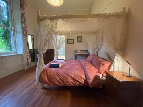 a bedroom with a canopy bed with a wooden floor at Shannon River House & Gardens in Limerick