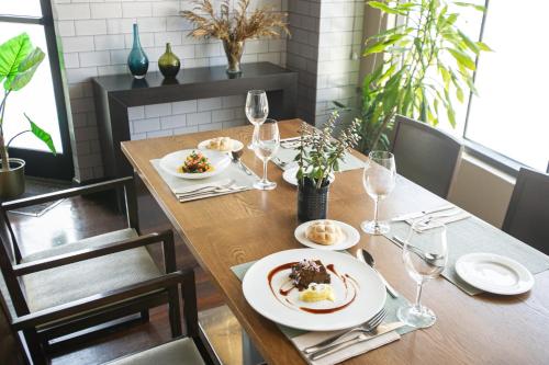 a wooden table with plates of food and wine glasses at AZZ Asturias LangreHotel & Spa in Langreo