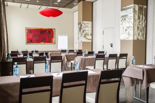 a conference room with tables and chairs and a painting at AZZ Asturias LangreHotel & Spa in Langreo