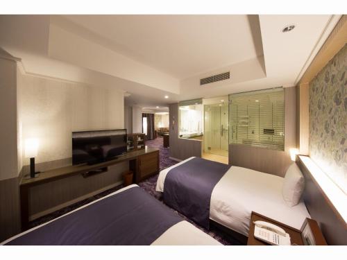 a hotel room with two beds and a flat screen tv at Kokusai 21 International Hotel in Nagano