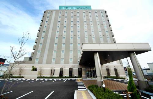 a large building with a parking lot in front of it at Hotel Route-Inn Niigata Nishi Inter in Niigata