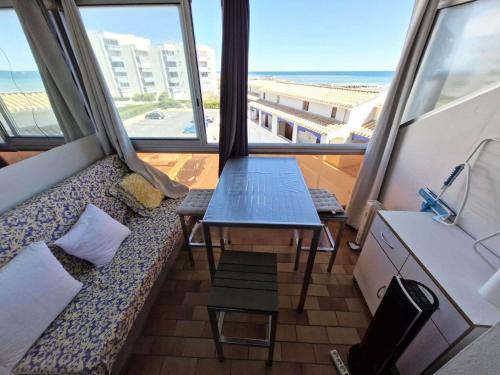 Cette chambre dispose d'un canapé et d'une table avec vue sur la plage. dans l'établissement Résidence L'escale - STUDIO 4 PERSONNES LE BARCARES. Réf: 8ESC_207 MAE-9473, au Barcarès