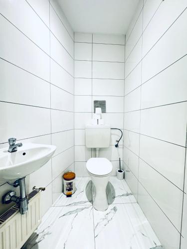 a white bathroom with a toilet and a sink at Comfy & Cozy 4BR Shared Apt next to Kaufpark Alterlaa in Vienna