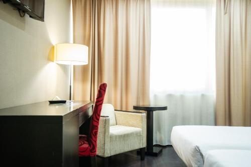 a hotel room with a desk and a chair and a bed at AZZ Asturias LangreHotel & Spa in Langreo