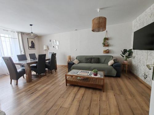 a living room with a green couch and a table at Maison de ville le 101 - 3 chambres - garage in Angoulême
