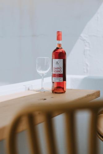 a bottle of wine sitting on a table with a wine glass at Trouhalos Apartment in Livadion