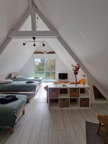 Cette chambre mansardée comprend deux lits et un bureau. dans l'établissement Domaine de Kervernet, à Saint-Lyphard