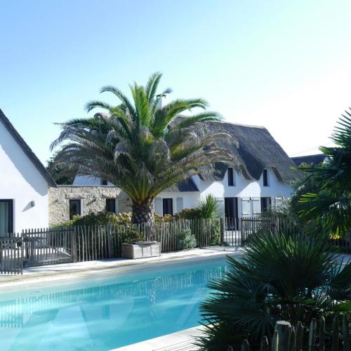 une maison avec un palmier et une piscine dans l'établissement Domaine de Kervernet, à Saint-Lyphard