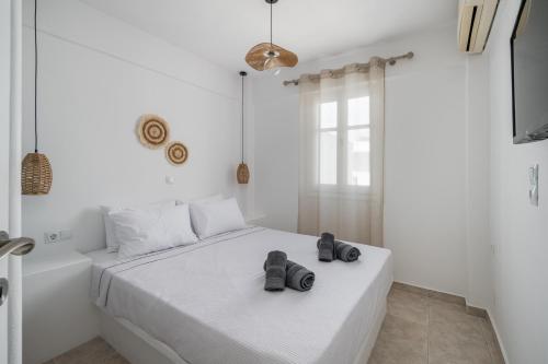 a white bedroom with a bed with two shoes on it at Trouhalos Apartment in Livadion