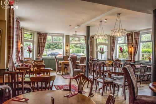 een restaurant met tafels, stoelen en ramen bij The Robin Hood Inn in Rowlands Castle