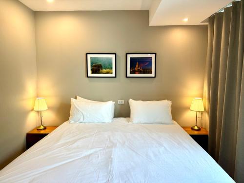 a bedroom with a large white bed with two lamps at Rimm49 Bangkok in Bangkok