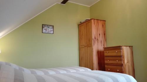 a bedroom with a bed and a wooden dresser at Słoneczna Zagroda - Sunny Ridge Farm in Łączna