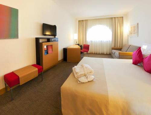 a hotel room with a bed and a living room at Novotel Tunis in Tunis