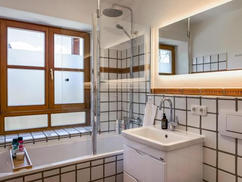 Un baño con lavabo, bañera y espejo. en Apartment für 6 - Bergblick, Balkon, Kamin, Kino, Yoga, Parkplatz, en Garmisch-Partenkirchen