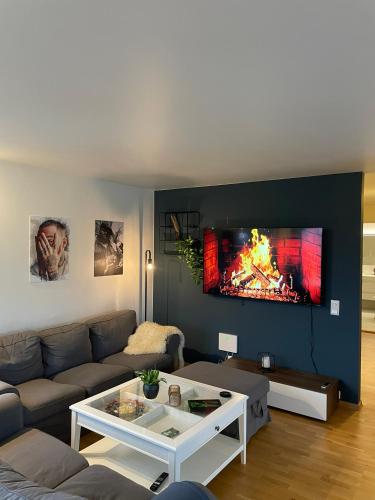 a living room with a couch and a tv on a wall at Exclusive apartment with great views close to city center in Svolvær