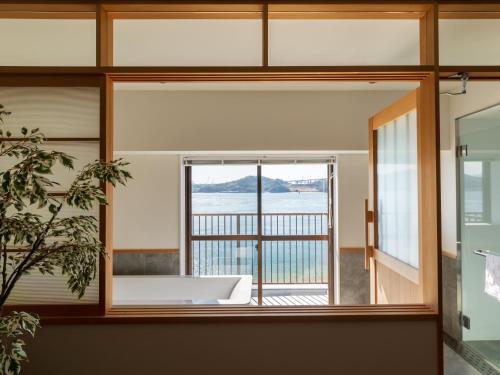 a room with a tub and a view of the water at Glamprook Shimanami in Imabari