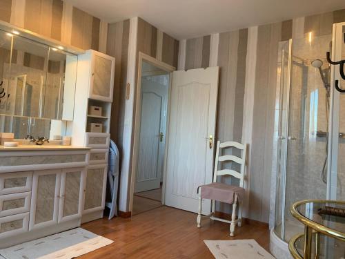 une salle de bain avec une douche et une chaise dedans dans l'établissement Maison Cléopâtre 4 minutes à pied de la plage 3 chambres véranda jardin parking privé, à Wimereux