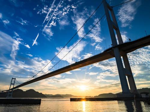 a bridge over the water at sunset at Glamprook Shimanami in Imabari