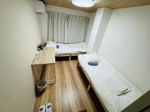 a small room with two beds and a window at Mori Hotel in Osaka