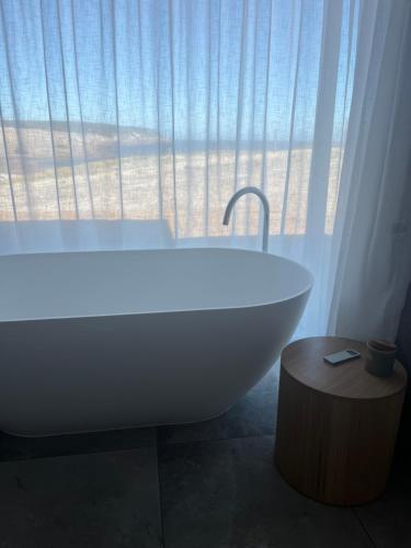 La salle de bains est pourvue d'une baignoire blanche et d'une fenêtre. dans l'établissement Coast, à Stokes Bay