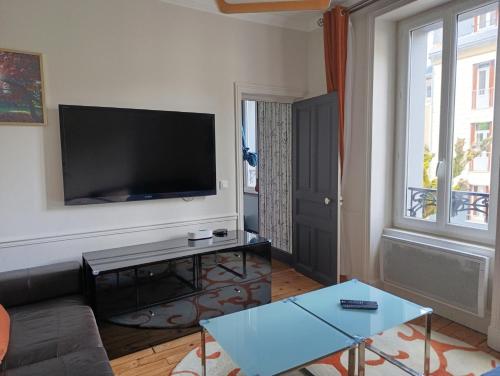 a living room with a couch and a flat screen tv at La villa de l'Angle - Maison familiale de charme - jusqu'à 10 voyageurs in Le Mont-Dore