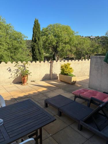 a patio with a table and benches and a wall at Auberge de Saugras in Argelliers