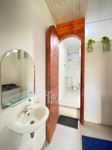 a bathroom with a sink and a toilet and a mirror at Evergreen Lodge in Padang