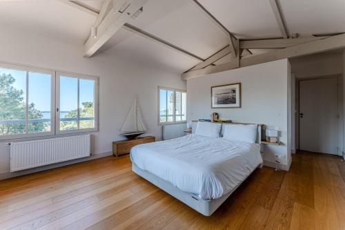 une chambre avec un grand lit blanc et du parquet dans l'établissement Villa Mistral Pyla-sur-Mer, à La Teste-de-Buch