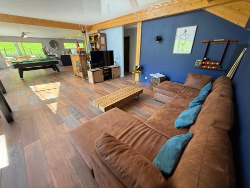 - un salon avec un grand canapé brun et une table dans l'établissement les anthocyanes CHAMBRE FORET, à Champagny