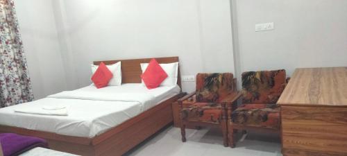 a bedroom with a bed and two chairs with red pillows at Hotel Abhi family guest house in Lucknow