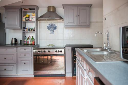 une cuisine avec des armoires blanches, un évier et une cuisinière dans l'établissement 5-room apartment Place de la Comédie, à Montpellier