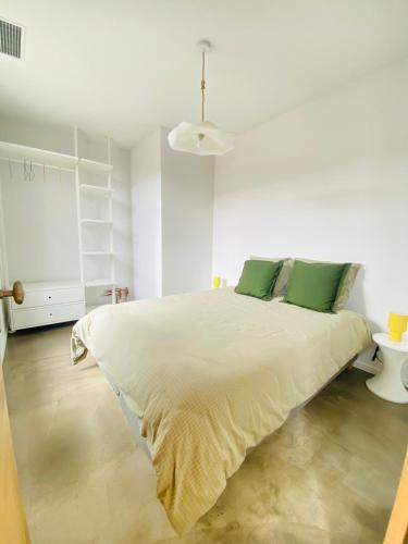 une chambre blanche avec un grand lit avec des oreillers verts dans l'établissement L'Oustalet Arles, à Arles